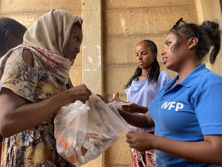WFP staffer handing food to a woman