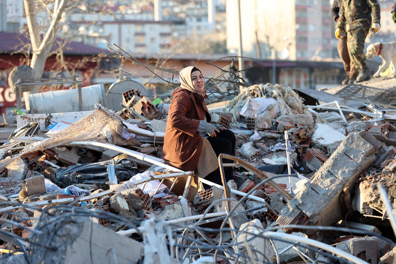 a woman sits on the rubble of a destroyed building in Kahramanmaras