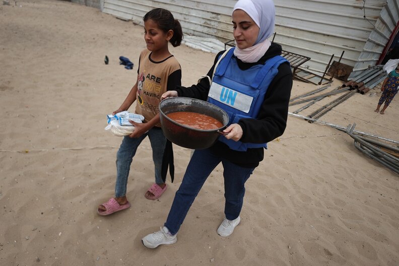 A girl and a WFP staff member carrying food aid in Gaza. © WFP