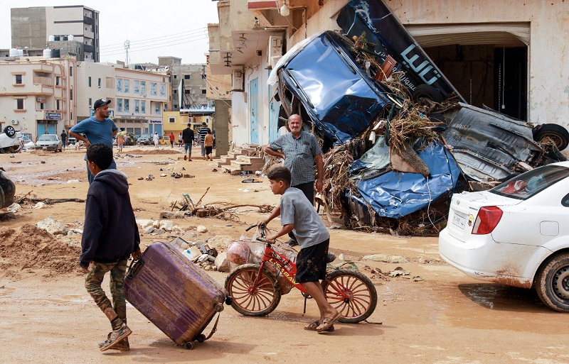 a boy pulls a suitcase past debris in a flash-flood damaged area in Derna, eastern Libya, on September 11, 2023. Flash floods in eastern Libya killed more than 2,300 people in the Mediterranean coastal city of Derna alone, the emergency services of the Tripoli-based government said on September 12. © AFP