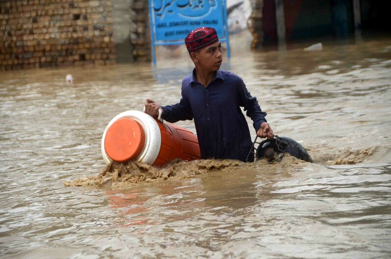 In this photo, a young boy wades through a flooded area in Peshawar, Khyber Pakhtunkhwa, Pakistan on August 27, 2022.