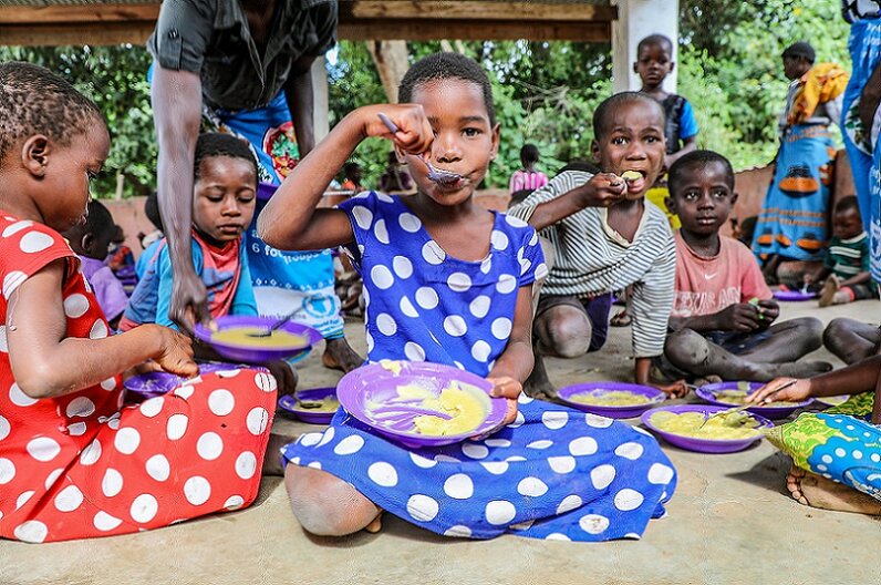 A group of children eating hot meals provided through one of WFP's school feeding programmes in Malawi.  © WFP/Simon Pierre Diouf