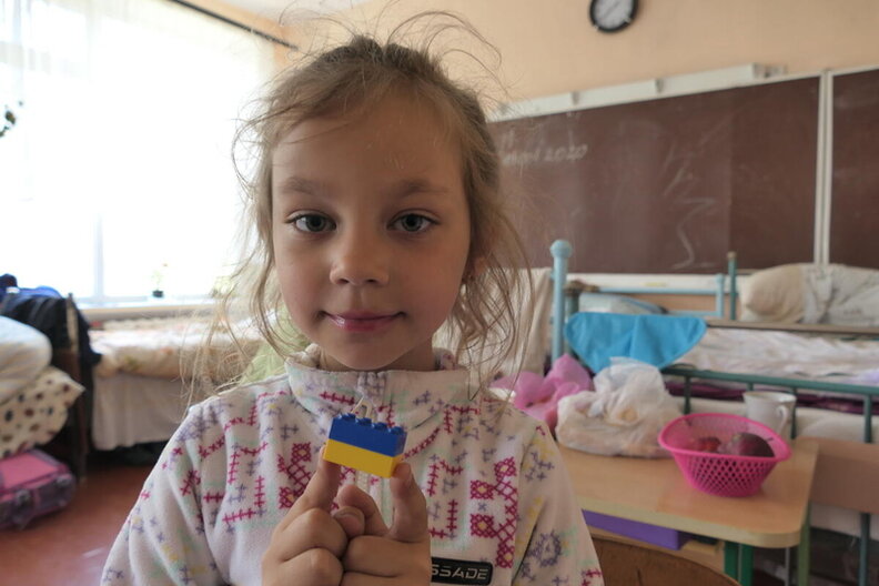 © WFP/Edward Johnson A girl holding up bricks in the colors blue and yellow, in Severynivka School which now houses displaced people from all over Ukraine