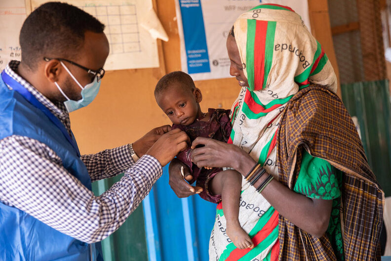 In this photo a WFP staff member chats Mido and her youngest daughter Fatun at the WFP funded malnutrition clinic in Kabasa, Dolow. © WFP/Samantha Reinders