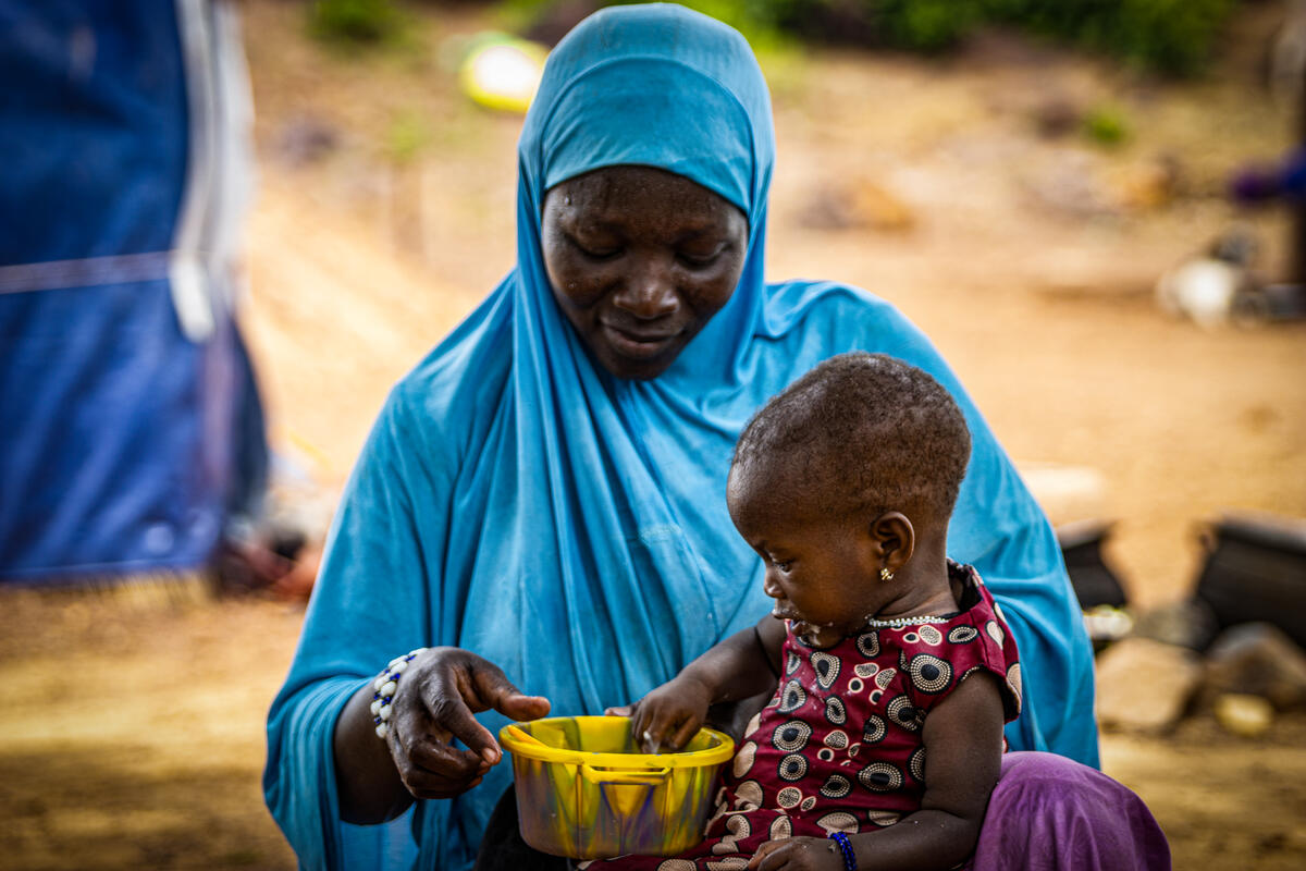 A 10-month-old girl puts her hand in the plate containing the fortified porridge to drink it by hand.  © WFP/Cheick Omar Bandaogo