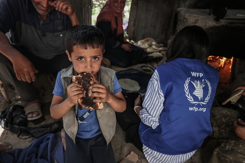 Mostafa is munching on freshly baked Manakish made with wheat flour, and olive oil that his parents just received in their WFP food basket © WFP/Ali Jadallah
