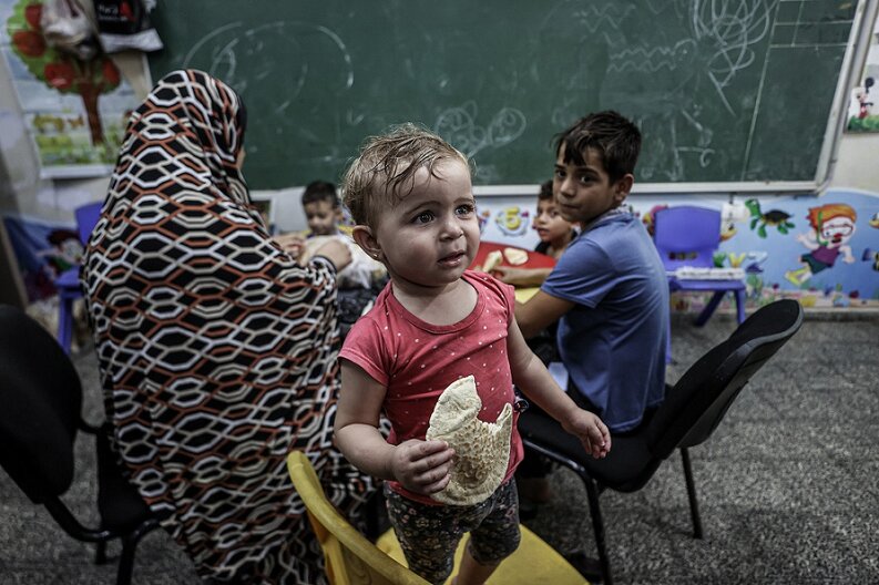 © WFP/Ali Jadallah A little girl holding bread in her hand which WFP had distributed.