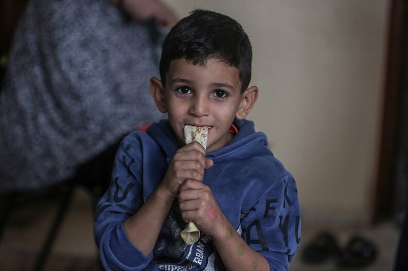 A little boy, one of Khitam's sons, is eating bread provided by WFP  © WFP/Ali Jadallah