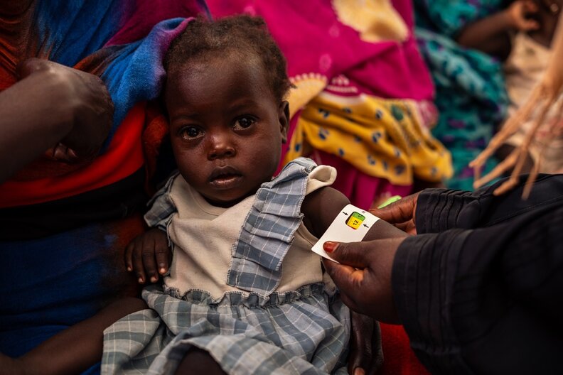 Sittna (two years old) daughter of Magedah while getting her MUAC measurements taking by the nutrition officer at the WFP-Supported nutrition centre of Philippe in Portsudan. © WFP/Abubakar Garelnabei