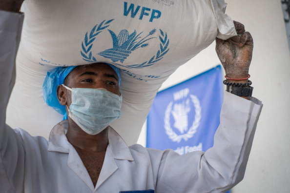 Photo: WFP/Mohammed Sami, humanitarian workers are carrying the food bags from the store into the truck. 