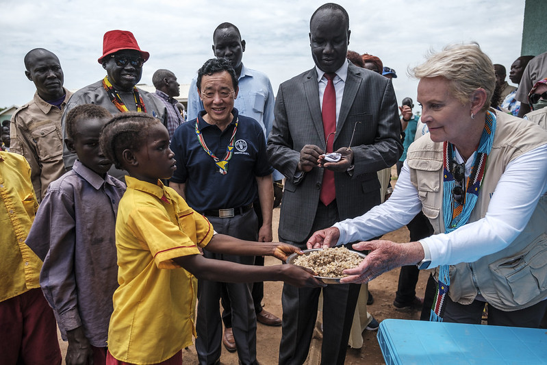 FAO/IFAD/WFP/Eduardo Soteras. Aweil, South Sudan - WFP Executive Director Cindy McCain (R) handles a plate of food to a student during a visit to the Udhaba Primary School, in the village of Udhaba, as part of the principals of Rome-based Agencies official visit to South Sudan.