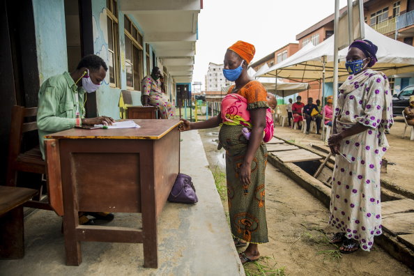 Photo: WFP/Damilola Onafuwa. Women practicing social distancing as they get their food vouchers verified at the National Home Grown School Feeding Programme at Adekunle Anglican Primary School, Makoko, Lagos, Nigeria. 