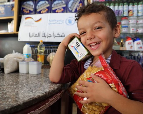 Photo: WFP/Khaled Abu Shaaban, a child in the Gaza Strip enjoying buying his favourite food at a local shop using WFP electronic voucher. 