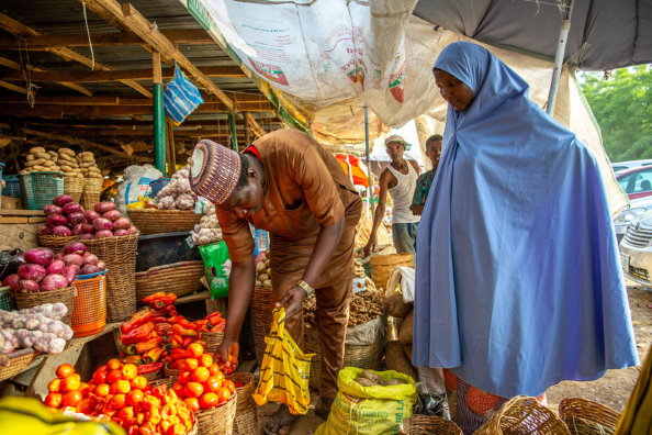 WFP/Arete/Adetona Omokanye, Women buys tomatoes in Yankaaba Market in Kano, Nigeria on 11th April, 2021. Many people in Nigeria are struggling to support their families due to rapidly escalating food prices.