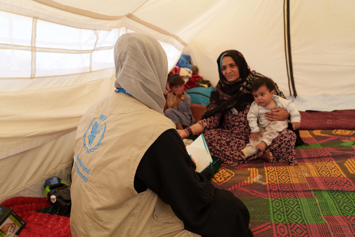 WFP/Hasib Hazinyar, A female WFP monitor speaks to a survivor of the earthquake in a tent put up next to the rubble of her home. 