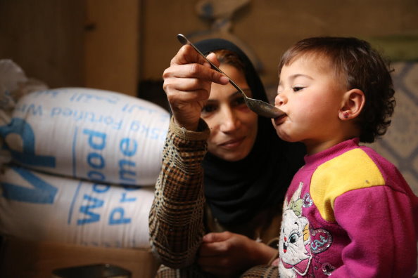 Photo: WFP/Abeer Etefa, Woman displaced with her family from Douma in rural Damascus to Adra - feeding her 18 month old daughter lunch.