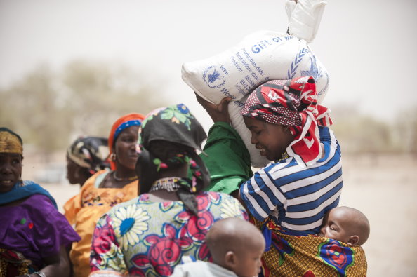 Photo: WFP/ Rein Skullerud, A woman shoulders a bag of WFP food during a distribution in Niger.