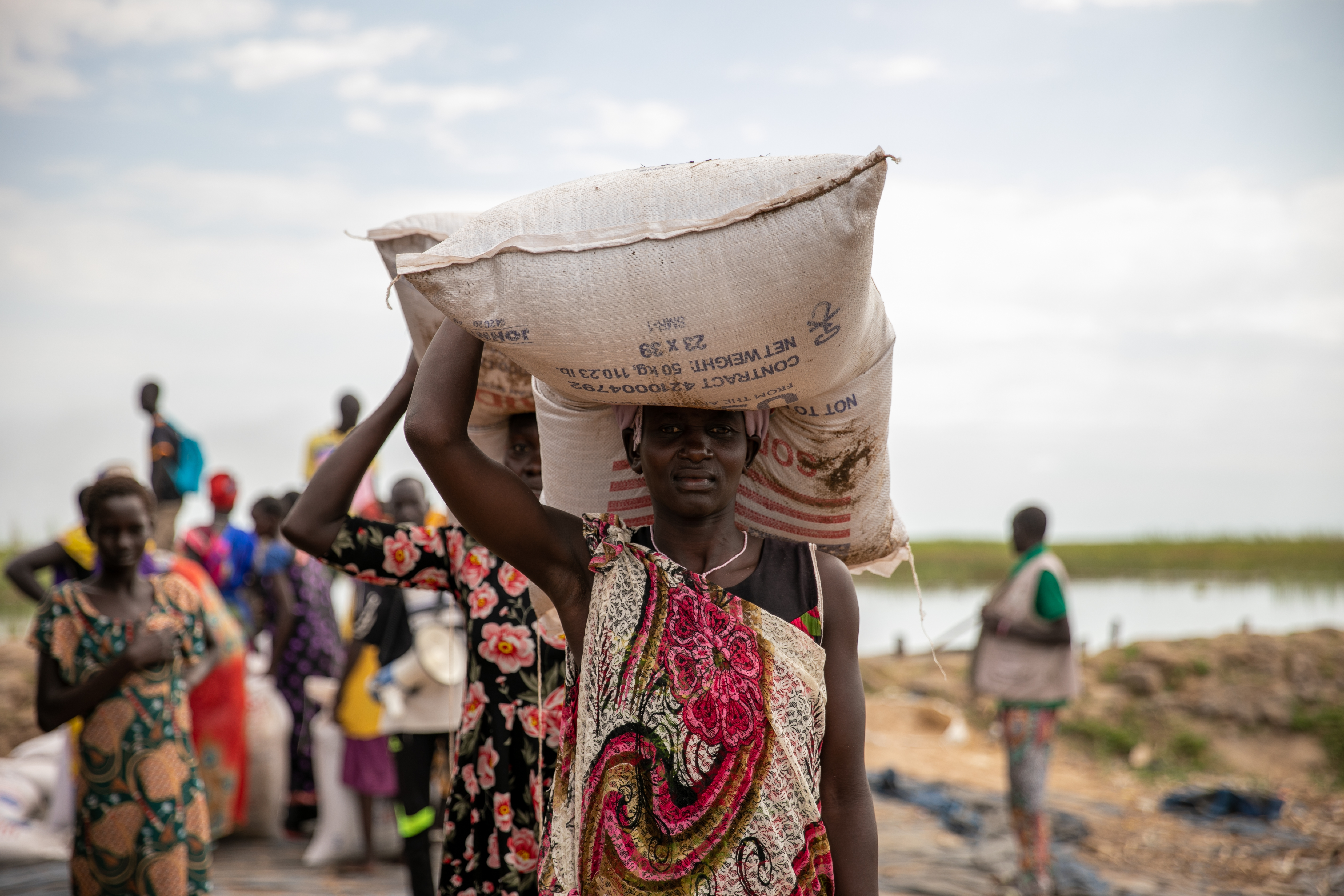 Women offload food at Nyal port, Unity State, where WFP transports food via canoe to avoid costly airdrops. Credit: Eulalia Berlanga