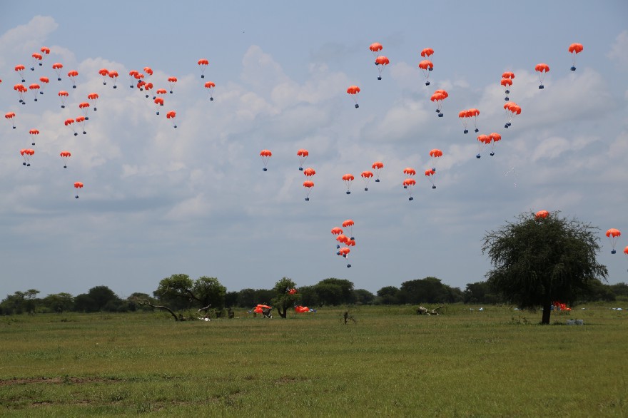 Boxes loaded with vegetable oil drift slowly to the ground from 300 metres in the air. Photo: WFP/Peter Smerdon