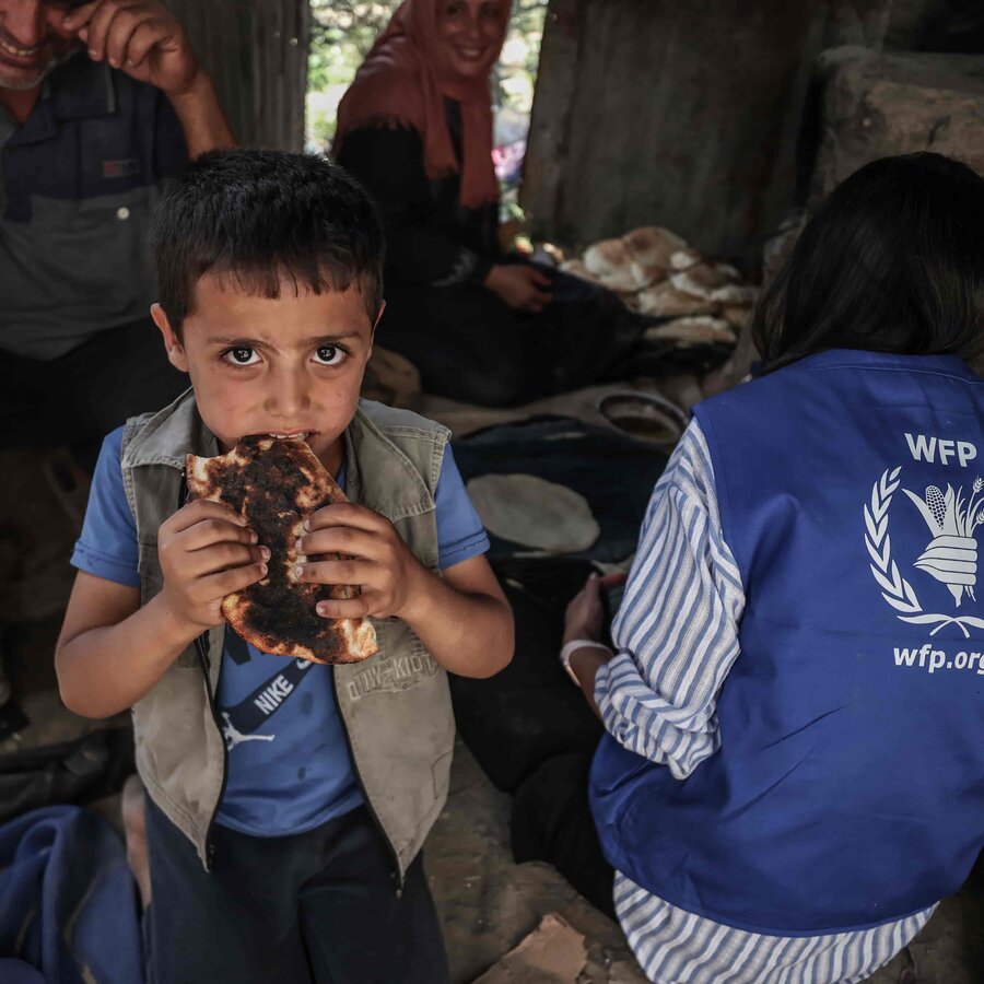 A young boy eats bread from WFP in Gaza, where more than 1 million people face catastrophic hunger. Photo: WFP/Ali Jadallah