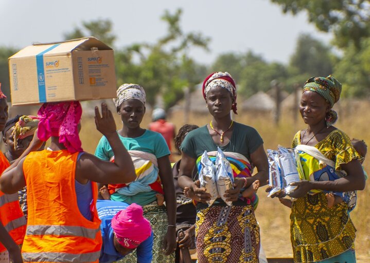 Women with a child on their back, have just received packets of Corn Soya Blend (CSB+).