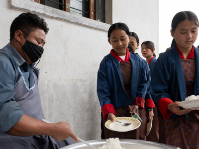 Schoolchildren queue to receive a hot school meal, supporting nutrition, learning and healthy development through a school feeding programme.