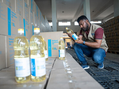 WFP employee inspecting boxes of sunflower oil procured for WFP food assistance baskets.