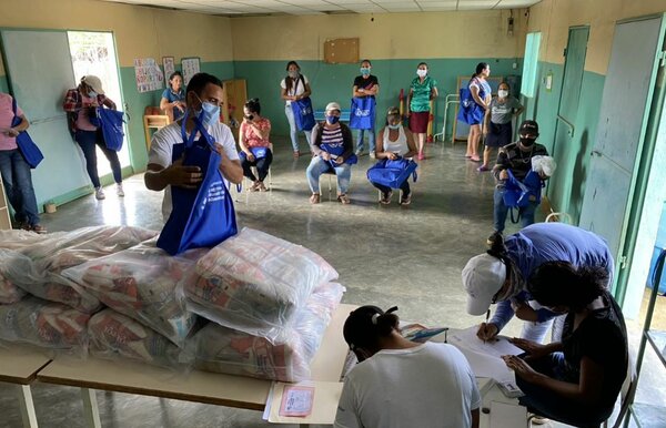 Un padre de familia recibe la ración escolar para llevar a casa. 