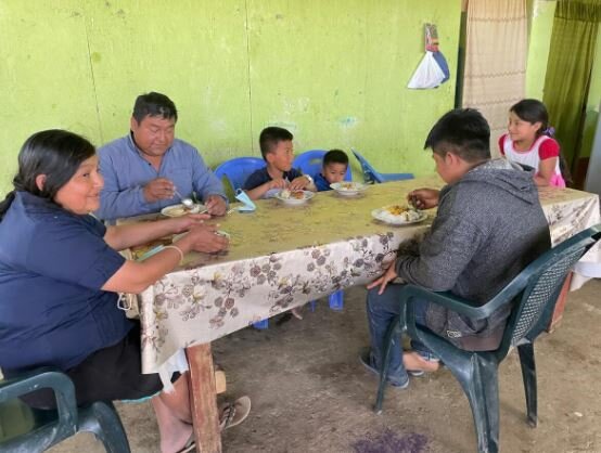 María, her husband Vicente and children sit at the table to eat lunch.