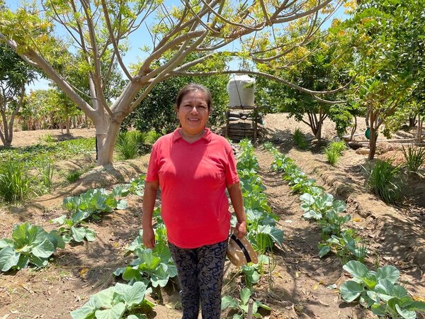 Noemí stands in front of her orchard.