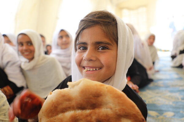 Nafisa, in Grade 2, receives Bread+ made from fortified wheat flour, soy flour, raisins and walnuts, a nutritious and delicious school midday snack for primary boys and girls. Photo: WFP/Sadeq Naseri