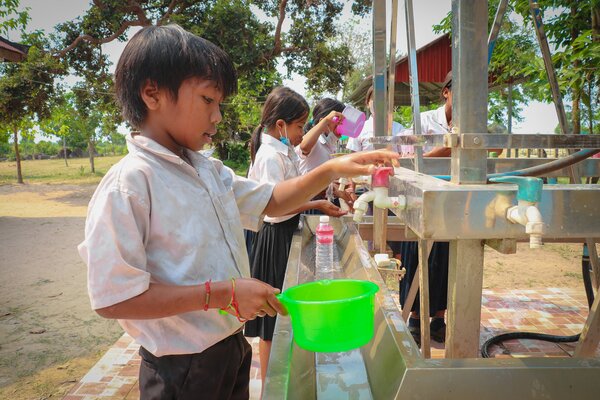 Children wash up at some taps after lunch