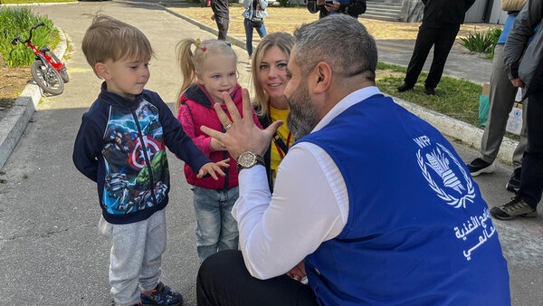 WFP staff playing with a boy and a girl in front of a basement shelter in Kharkiv