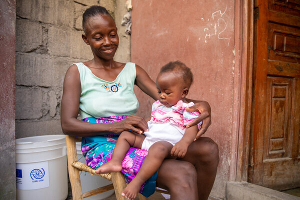 A woman holds her baby while sitting on her chair.