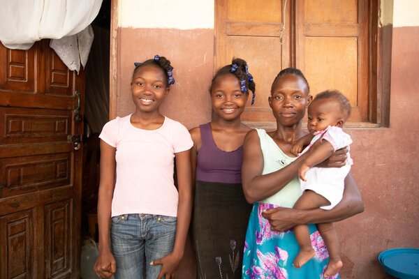 A Haitian woman and her three daughters standing in front of their home in Haiti.