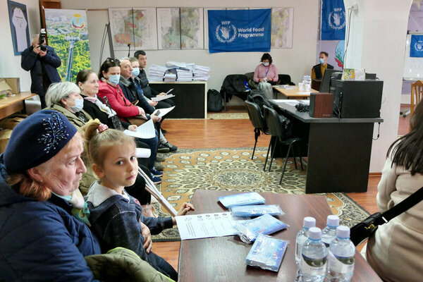 Vera, a Moldovan, waits in line at the newly set-up WFP base in Chisinau, with the 7-year-old daughter of her Ukrainian guests. 