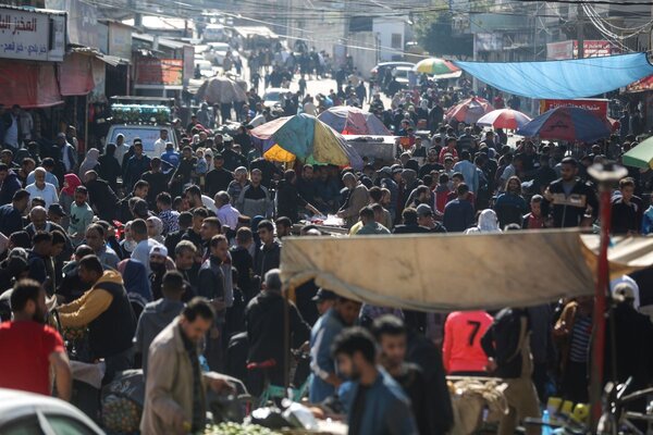 people crowd a market in Gaza looking for food