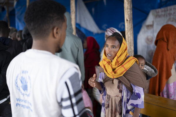 Ethiopian woman in orange headscarf speaks to man in WFP vest