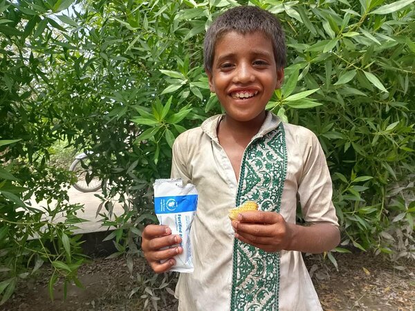 A boy smiles as he holds up a biscuit pack