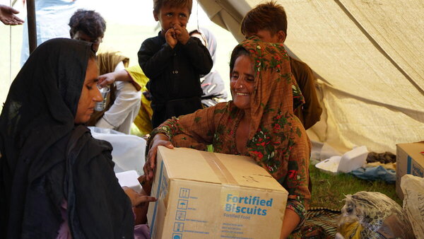 A woman carries a box of fortified biscuits on her shoulder