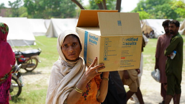 A woman carries a box of fortified biscuits on her shoulder
