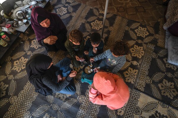 Aerial view of a family sat around a plate of food.