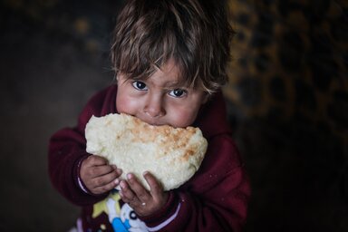 A little boy earing freshly made bread.