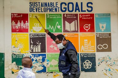 A World Food Programme (WFP) staff member teaches David about the Sustainable Development Goals at a distribution centre for the National Home Grown School Feeding Programme in Adekunle Anglican Primary School, Makoko, Lagos, Nigeria.