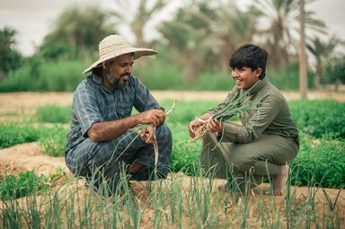 WFP/Mehedi Rahman a man and a child are laughing and sitting in a field