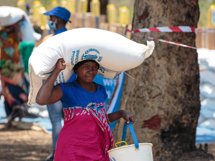 a woman is carrying a WFP sack over her head