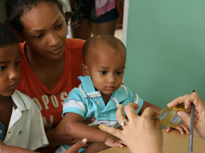 Mother and her two children receiving nutritious food assistance from WFP staff in Dominican Republic