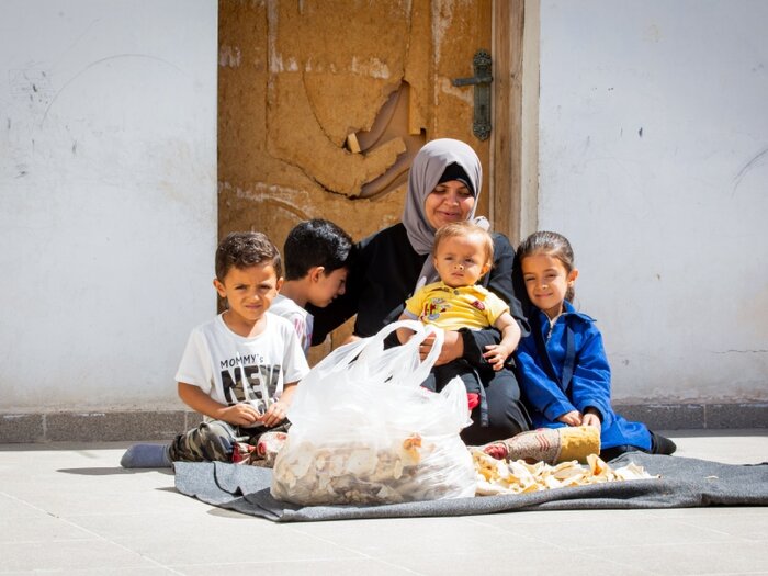 A refugee mother and her four children, residing in host communities, surrounded by a stark pile of dry bread.
