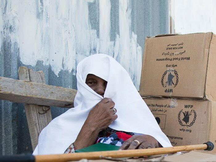 Woman with boxes of healthy food assistance distributed by WFP