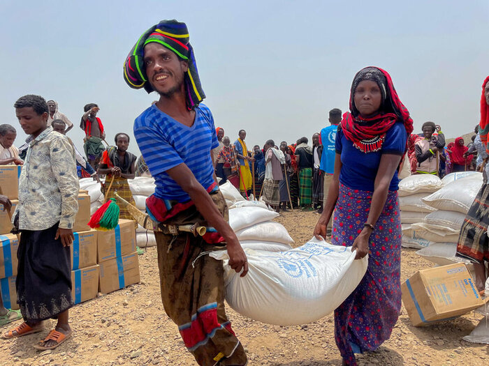 a man and a woman are carrying a WFP sack